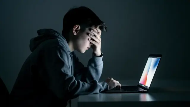 Person schützt sich mit Laptop und Smartphone vor Cybermobbing im Internet