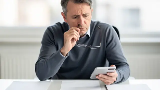 Beschäftigter prüft Unterlagen zu Erwerbsminderungsrente und Abfindung am Schreibtisch