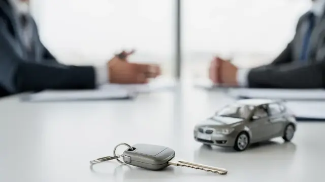 Geschäftsmann unterschreibt Leasingvertrag neben Firmenfahrzeug für finanzielle Flexibilität