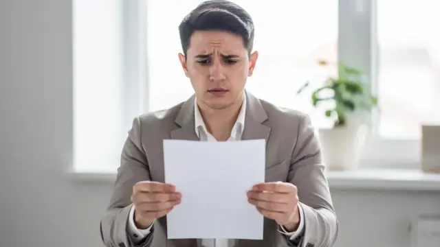 Arbeitnehmer liest Dokument zur Kündigung vom Arbeitgeber zu Hause