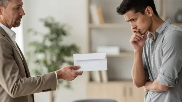 Mann liest Kündigungsschreiben im Büro mit ernster Miene